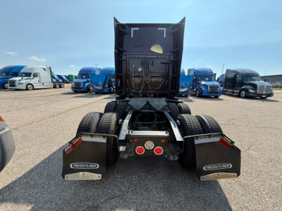 Rear view of a 2022 Freightliner Cascadia 126 tractor with fifth wheel revealed and dual rear axles; mud flaps labeled Freightliner; rear lights and reflective markers visible.