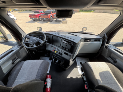 Freightliner Cascadia 126 cab interior showing steering wheel, dashboard, and driver seat with center-console controls.