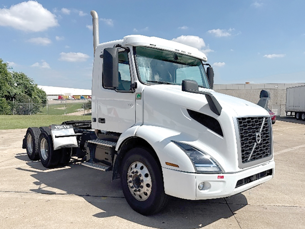 Volvo VNR 300 truck cab in white, front three-quarter view, with fuel tanks and dual rear axles visible.