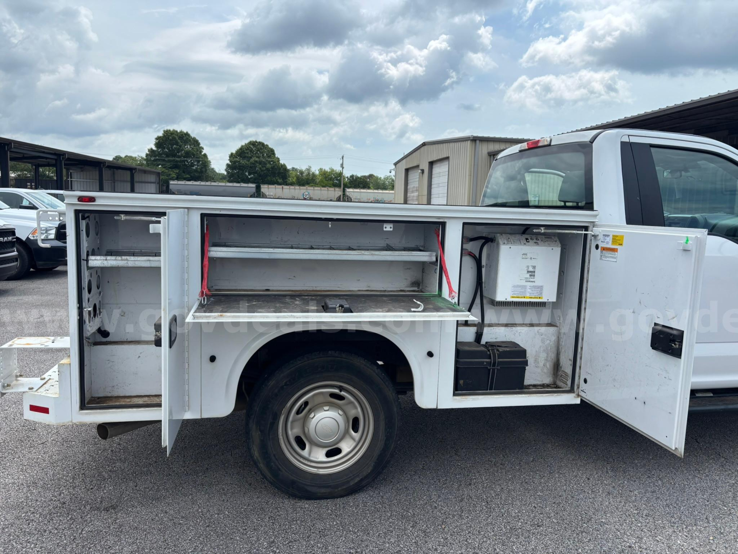 Ford F-250 utility service truck side compartments open showing tool/storage drawers and battery box.