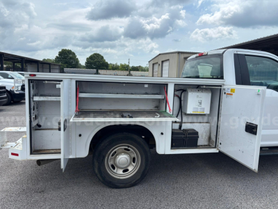Ford F-250 utility service truck side compartments open showing tool/storage drawers and battery box.
