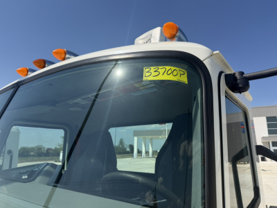 Truck cab front corner showing windshield with yellow tag B3700P, orange marker lights on roof, and side mirror. 2020 Mack PI64T truck.