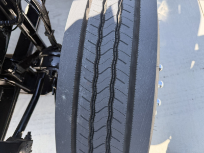 Tire and wheel well of a 2020 Mack PI64T truck showing a close-up of the front tire tread and adjacent suspension components.