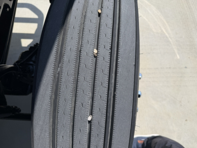 Tire tread view on a 2020 Mack PI64T truck showing the near-side wheel and tire with vertical grooves.