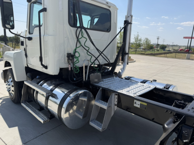 Truck cab of a 2020 Mack PI64T daycab with side tank and chrome fuel tanks, visible cab steps, and wiring harnesses; rear chassis and fuel tanks shown.