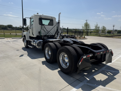 Truck rear three-quarter view showing semi tractor 6x4 chassis with dual rear axles and fifth-wheel, white cab, chrome fuel tanks, and dual tires.