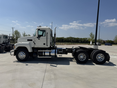 Truck chassis side view of a white 2020 Mack PI64T conventional daycab showing cab with fuel tanks and dual rear axles