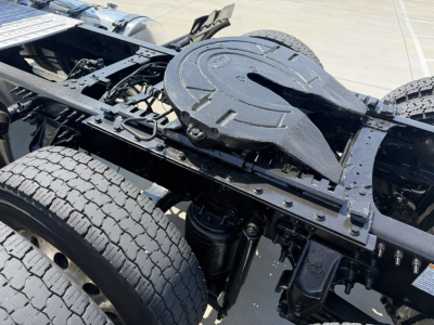 Rear chassis with fifth wheel and dual rear axles on a Mack PI64T truck; visible components include frame rails, air spring suspension, batteries not visible, fuel tanks unseen; no legible labels readable in this view.