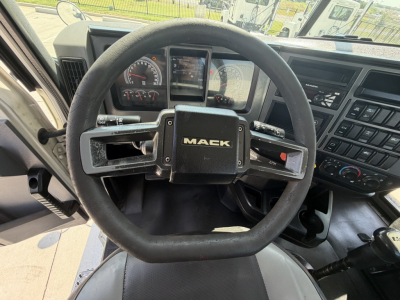 Mack PI64T truck interior steering wheel with Mack logo center, instrument cluster, and dashboard controls visible.