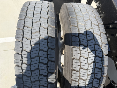 Two truck tires in the foreground with tread blocks visible; no text legible on the tires themselves.