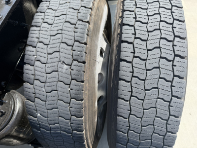 Dual Mack PI64T tires on a heavy truck axle showing tread pattern and wheel assembly.