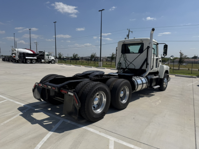 Mack PI64T truck tractor in a parking lot viewed from behind left rear, showing tandem axle configuration and fifth-wheel area.