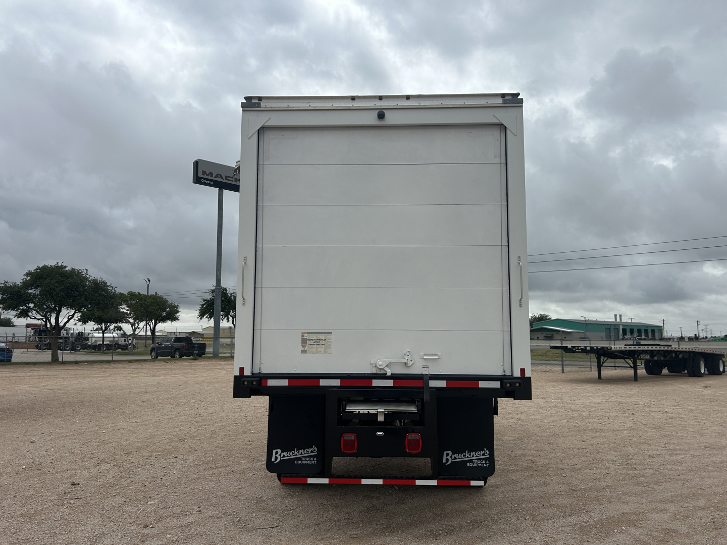Back view of a 2026 Mack MD6 refrigerated truck trailer with rear doors closed. Visible text on mudflap area shows 'Brakes...' and equipment marks; no legible brand text on doors.