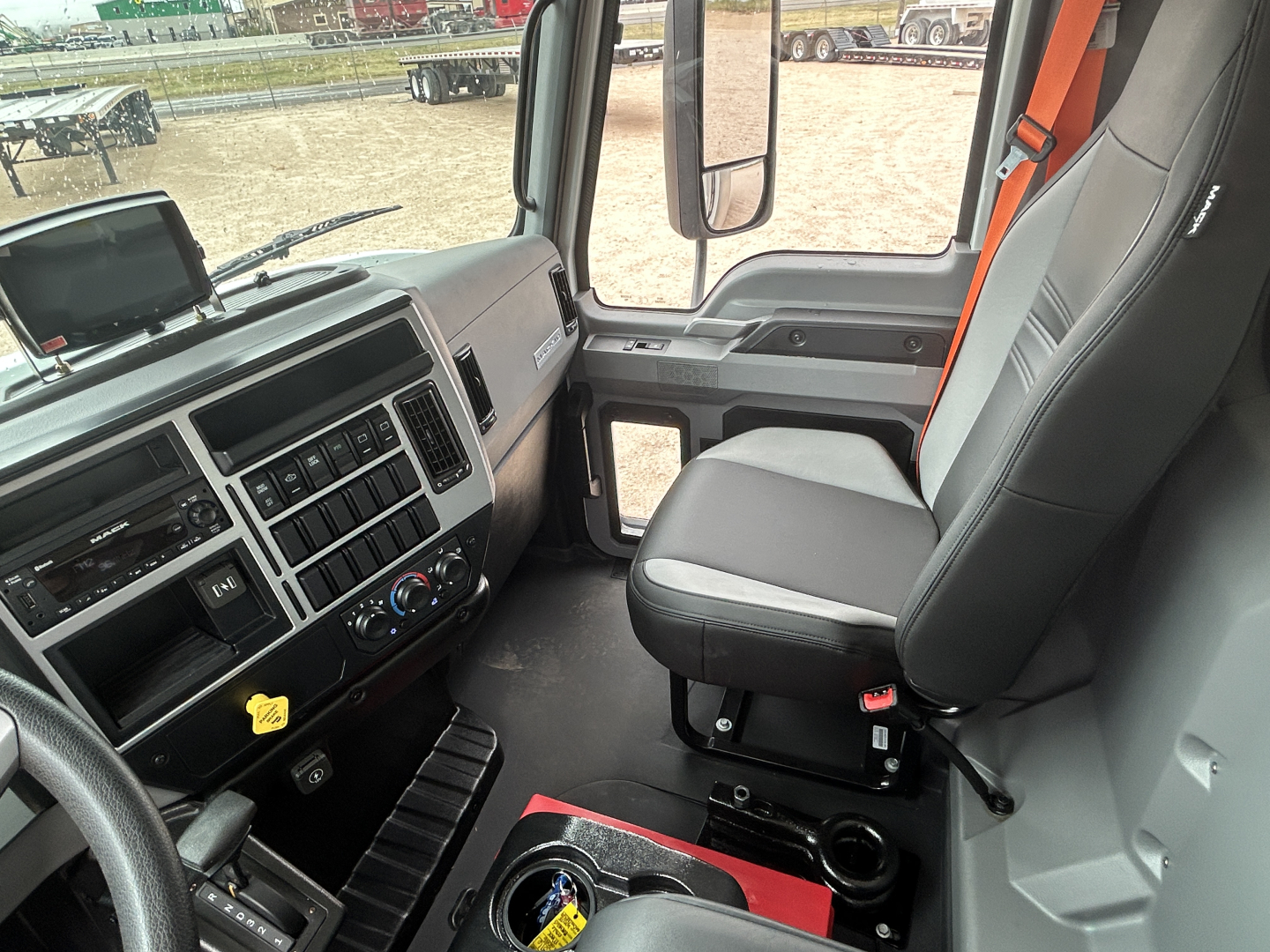 Truck interior cab view showing driver's seat and dashboard of a 2026 Mack MD6. Visible text includes vehicle controls and instrument panel; no legible model text on exterior.