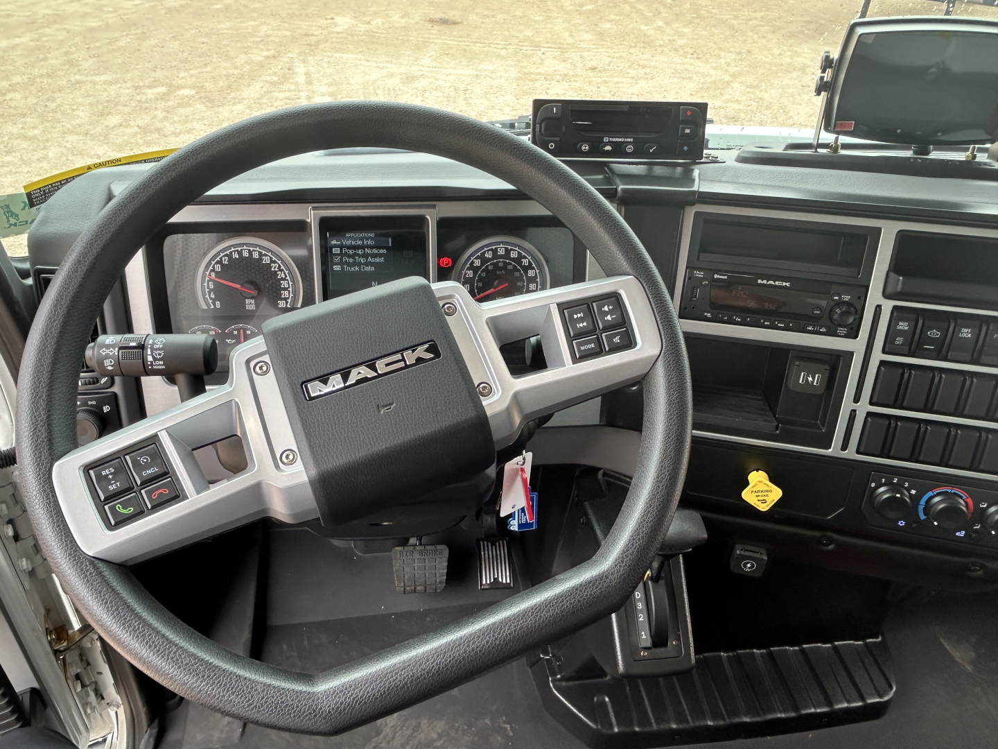 Cab interior of a Mack MD6 truck showing steering wheel with Mack logo, instrument cluster, center console, and dashboard controls.