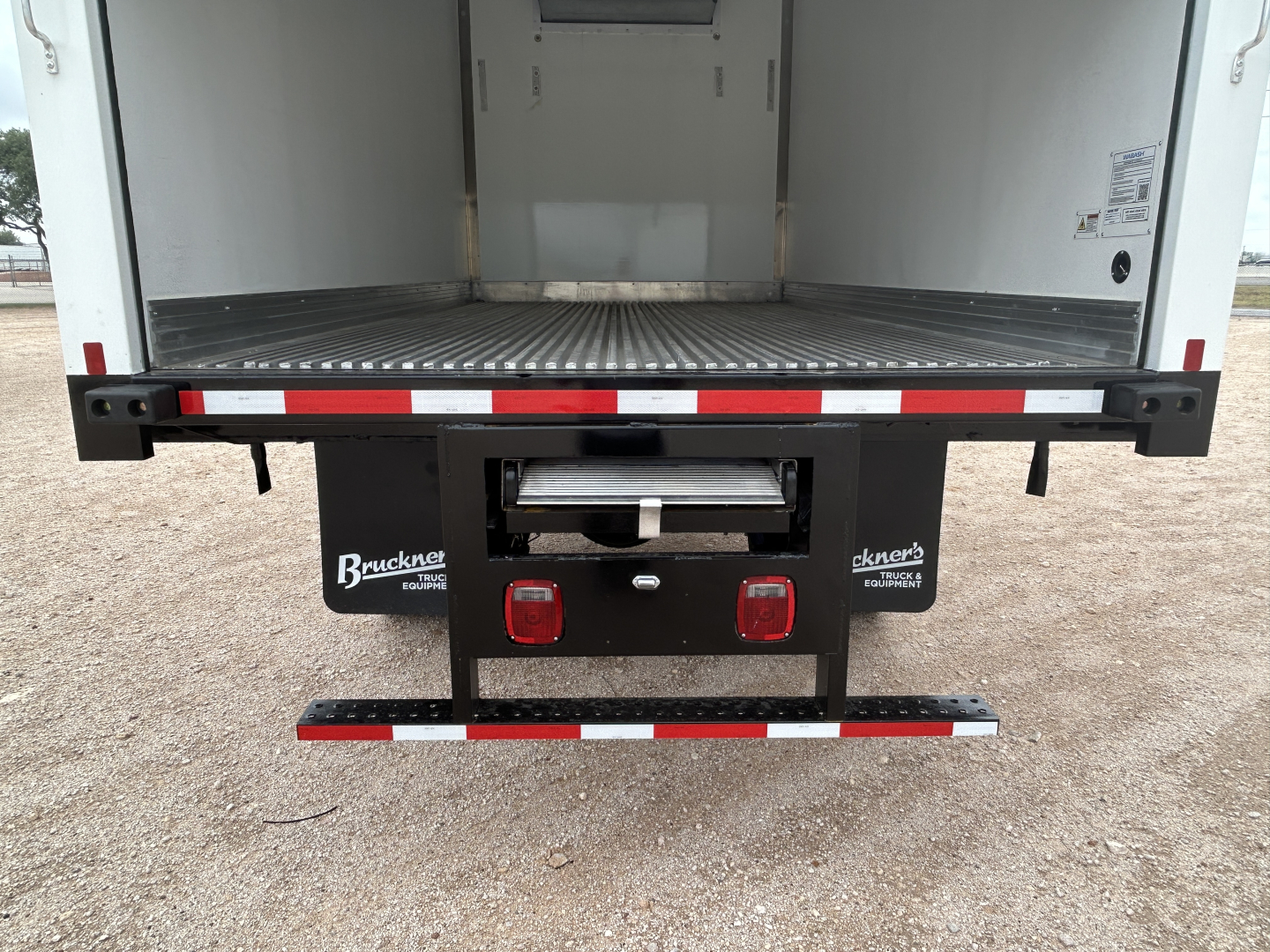 Mack MD6 refrigerated truck rear view showing open cargo area and rear bumper with taillights and reflectors.