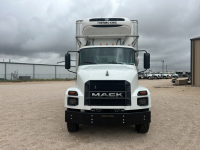 Front view of a white 2026 Mack MD6 refrigerated truck with Thermo King unit on top, large black Mack grille, black bumper, side mirrors, and cargo area visible in background.