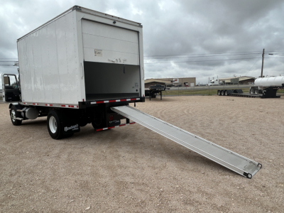 Truck side view with a ramp extension deployed from a refrigerated box truck—rear cargo area open, no visible branding on doors.