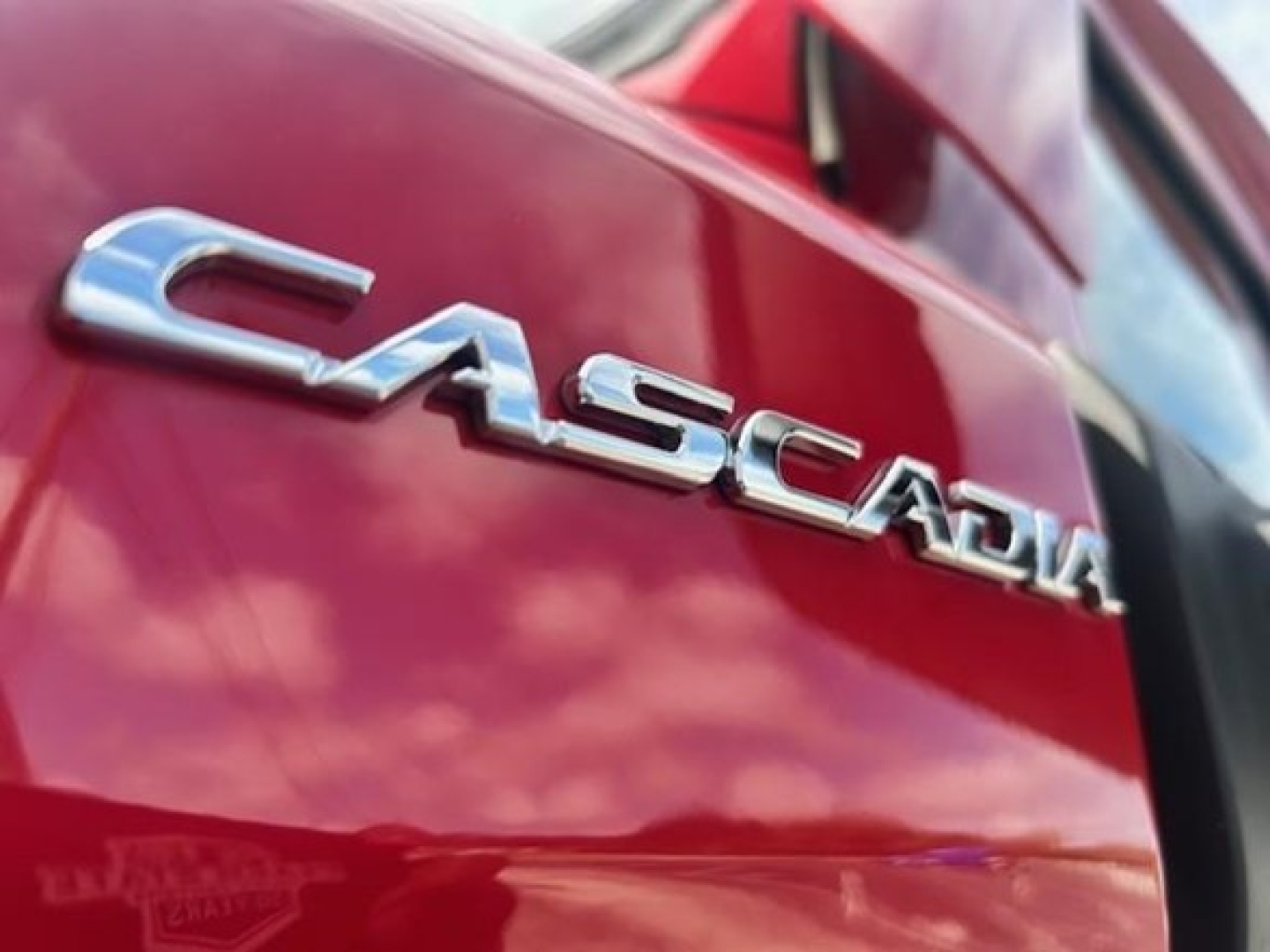 Casadia emblem on red Freightliner Cascadia 126 truck door badge close-up view.