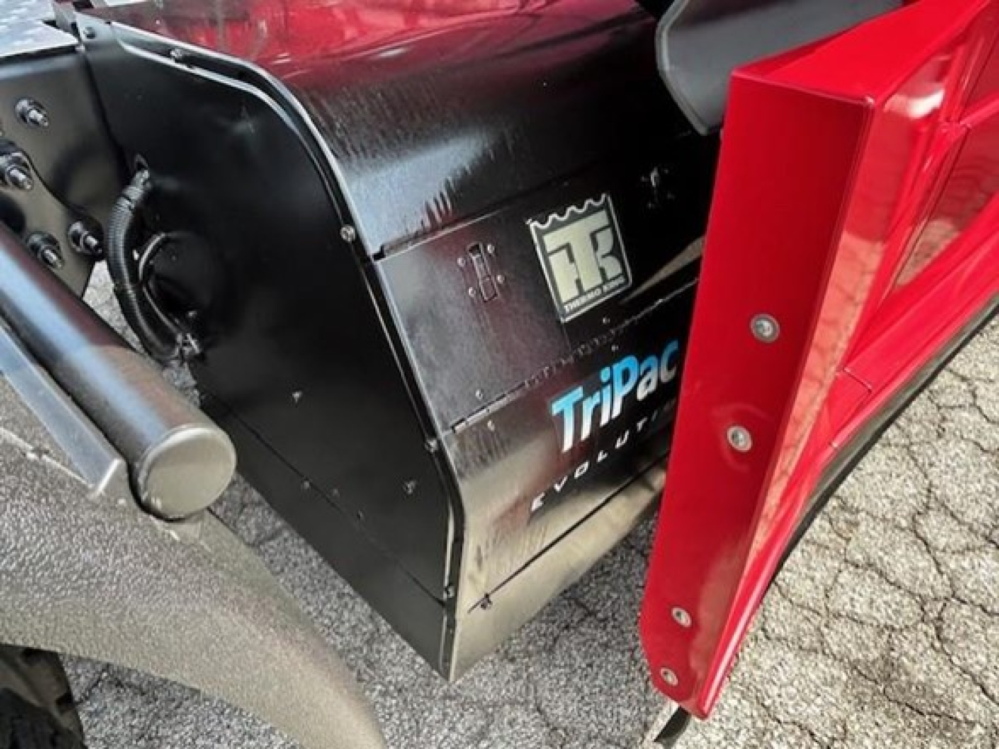 Truck interior components visible with black Toolbox labeled ‘Tripac Volvo’ near a red truck door in the foreground.