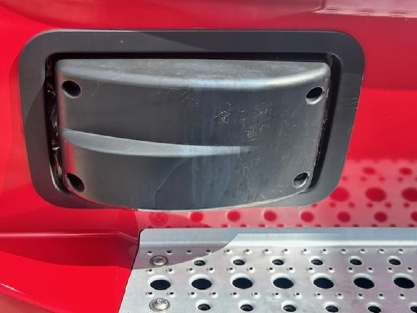 Freightliner engine bay focusing on a rectangular side panel/vent cover with four visible screws and a black plastic frame