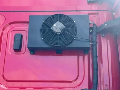Cascadia truck engine bay component showing a square radiator/AC condenser with a circular cooling fan mounted on a pink-red truck body.