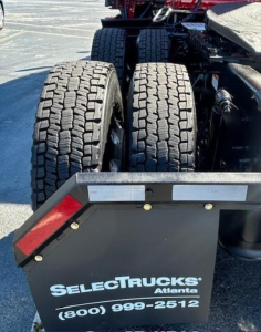 Truck rear showing dual rear axles with heavy-tread tires and a SelectTrucks Atlanta mudflap in view.