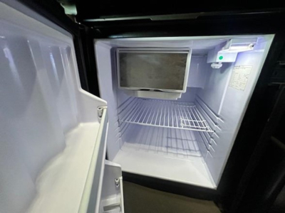 Freightliner Cascadia 126 sleeper cab interior fridge compartment open showing empty fridge/freezer with shelves.