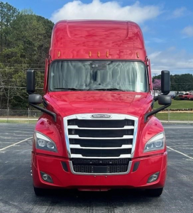 Freightliner Cascadia 126 front view showing bold chrome grille and red cab, black side mirrors, and windshield with sun visors.