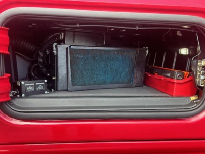 Trunk storage area of a 2023 Freightliner Cascadia 126 showing a compact radiator/condenser core and auxiliary components in the rear cab cradle.