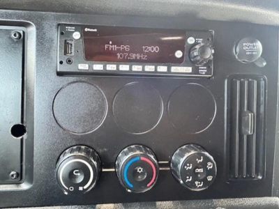 Dash panel of a Freightliner Cascadia showing radio head unit FM1-P6 12:00, climate control knobs, and power outlet. 