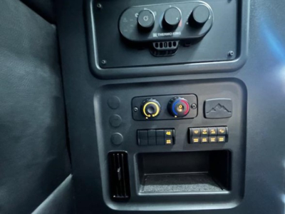 Dashboard controls and climate dials in a Freightliner Cascadia sleeper cab showing circular knobs and a small storage slot.