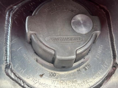 Fuel cap area of a Freightliner truck showing cap and surrounding surface with embossed text