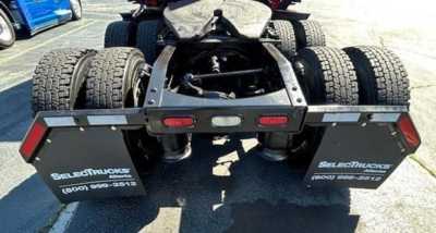Freightliner Cascadia truck rear showing chassis and dual rear axles, with bumper and mud flaps displaying SELECTTRUCKS branding.