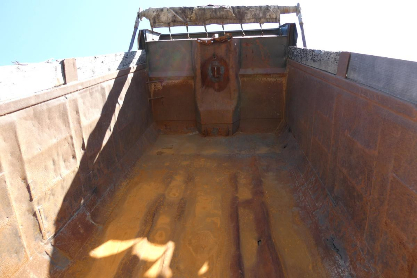 Dump bed interior of a 2000 Mack RD688S shown from tailgate, with rusted metal sides and bed floor, hydraulic tailgate mechanism at rear.