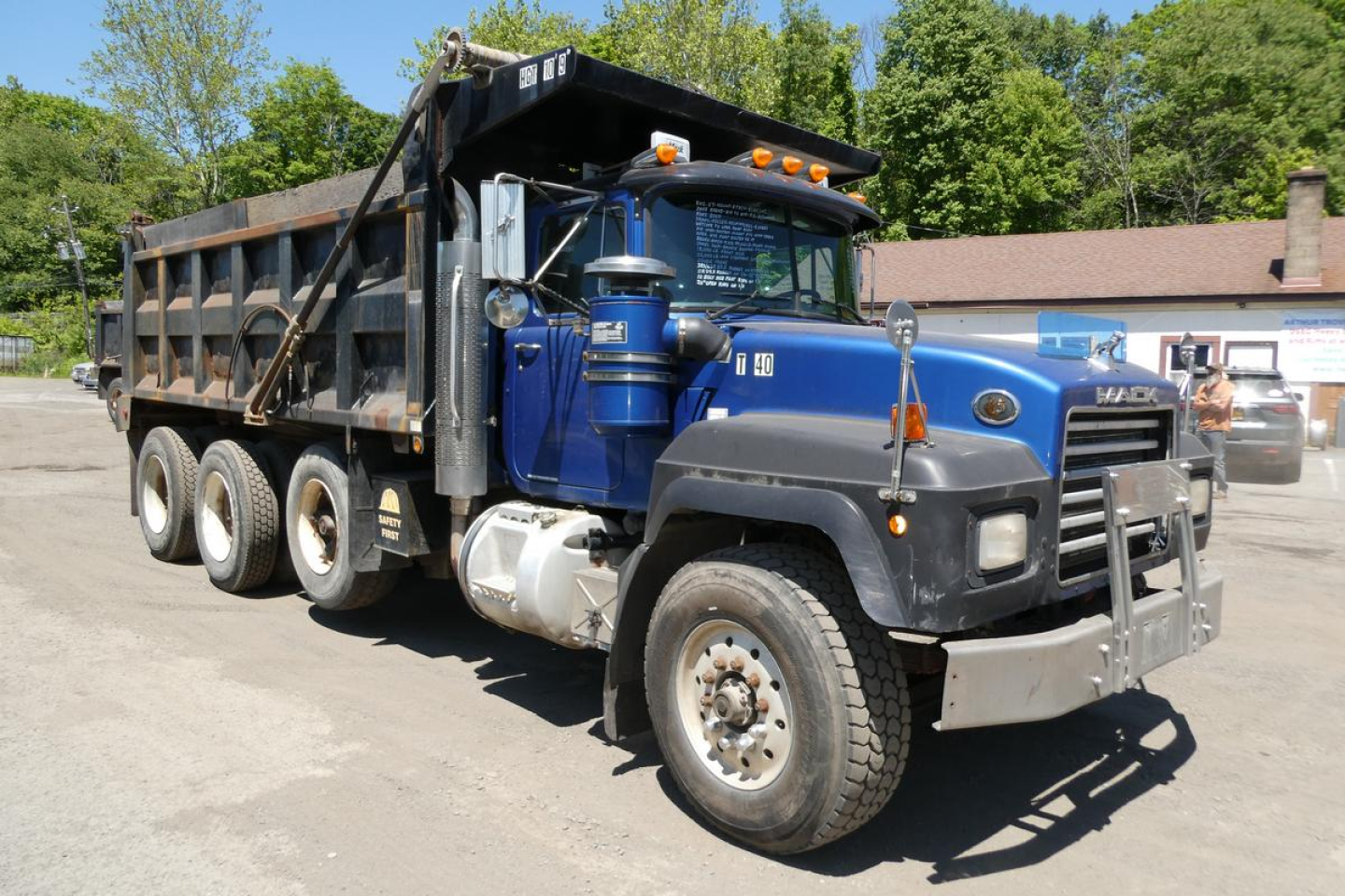 Dump truck cab and bed, blue Mack RD688S with dump bed open, front grille, large tires, and side mirrors visible.