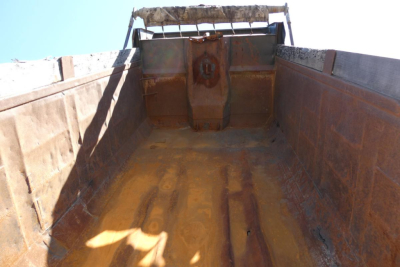 Dump bed interior of a 2000 Mack RD688S shown from tailgate, with rusted metal sides and bed floor, hydraulic tailgate mechanism at rear.