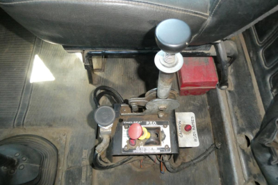 Truck interior showing gear shifter and control console with red start button and yellow knob, floor mat, and wiring harness in the cab of a Mack RD688S.