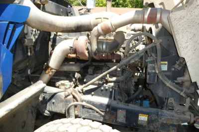 Engine bay with exhaust manifold and turbo piping, Mack RD688S truck components, hoses and belts visible.