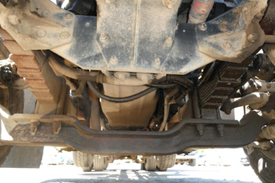 Underneath view of a 2000 Mack RD688S dump truck showing front axle, drivetrain, and suspension components with visible frame and undercarriage.