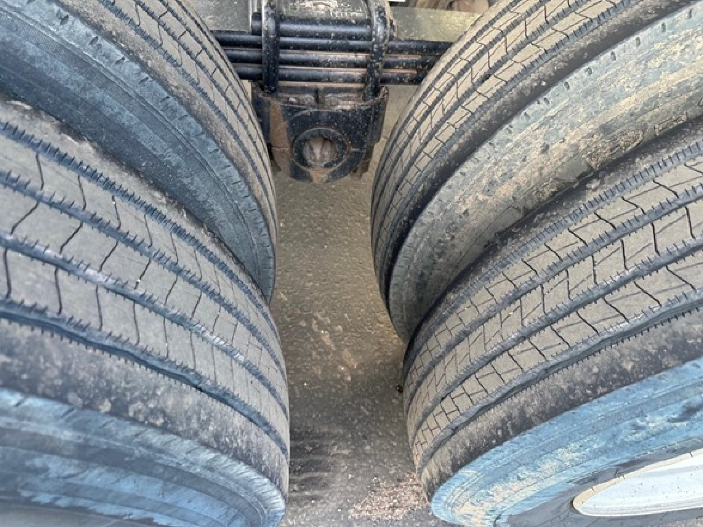 Trailer axle view showing dual rear tires of a Load King frameless rock end dump, heavy-duty suspension leaf springs visible between tires.