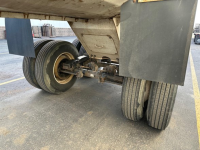 Trailer underside showing tandem axle wheels and suspension of a 2021 Load King 34' frameless rock end dump, wheel hubs, and dirt around the axles.