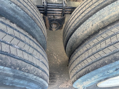 Trailer axle view showing dual rear tires of a Load King frameless rock end dump, heavy-duty suspension leaf springs visible between tires.