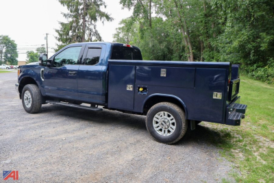 Ford F-350 Super Duty crew cab utility truck with utility bed side compartments, blue exterior, diesel engine, in-service condition.