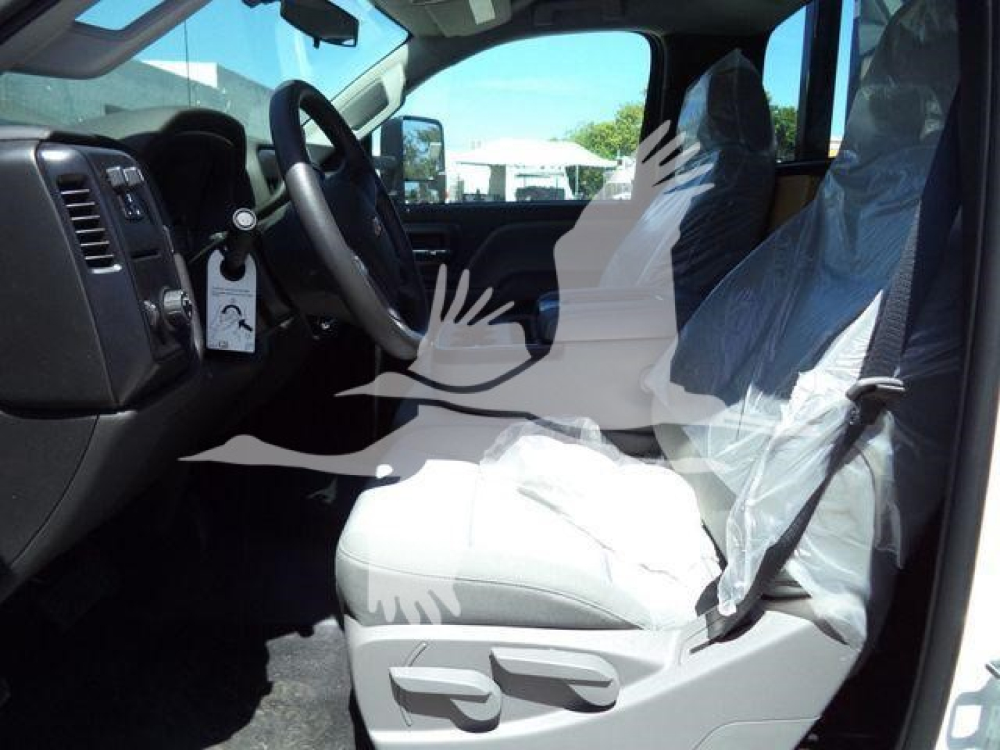 Interior of 2023 Chevrolet Silverado 6500HD rolloff showing steering wheel, dashboard, and front seats wrapped in plastic.