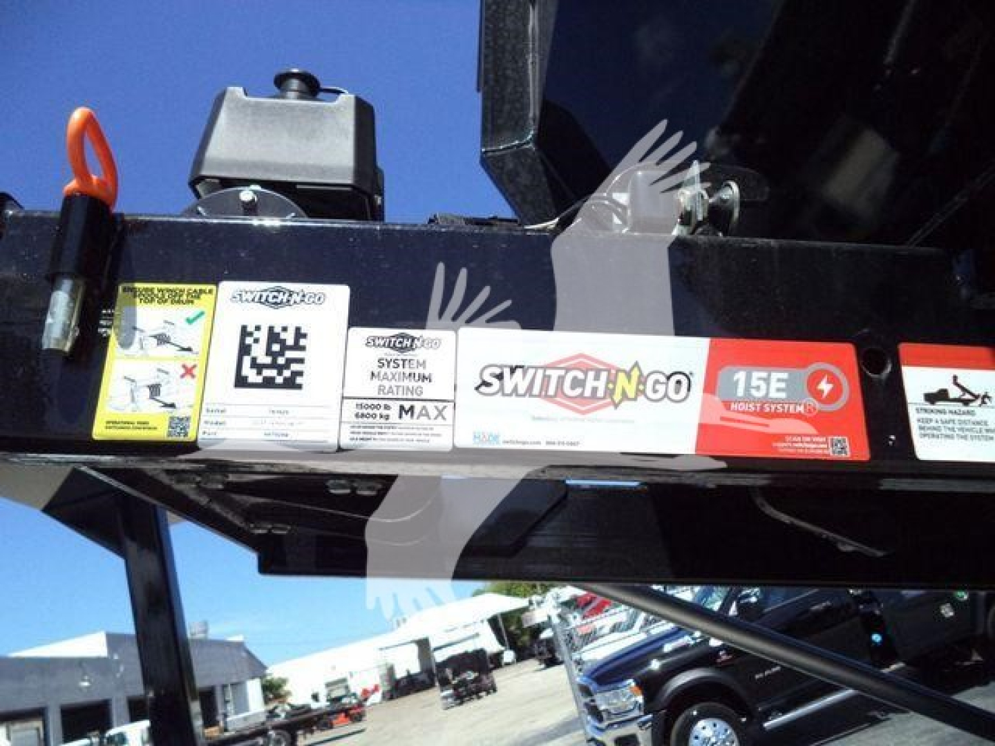 Trailer hitch area showing Switch-N-Go label, maximum rating sticker, QR code, and warning labels on a black frame of a 2023 Chevrolet Silverado 6500HD roll-off truck.