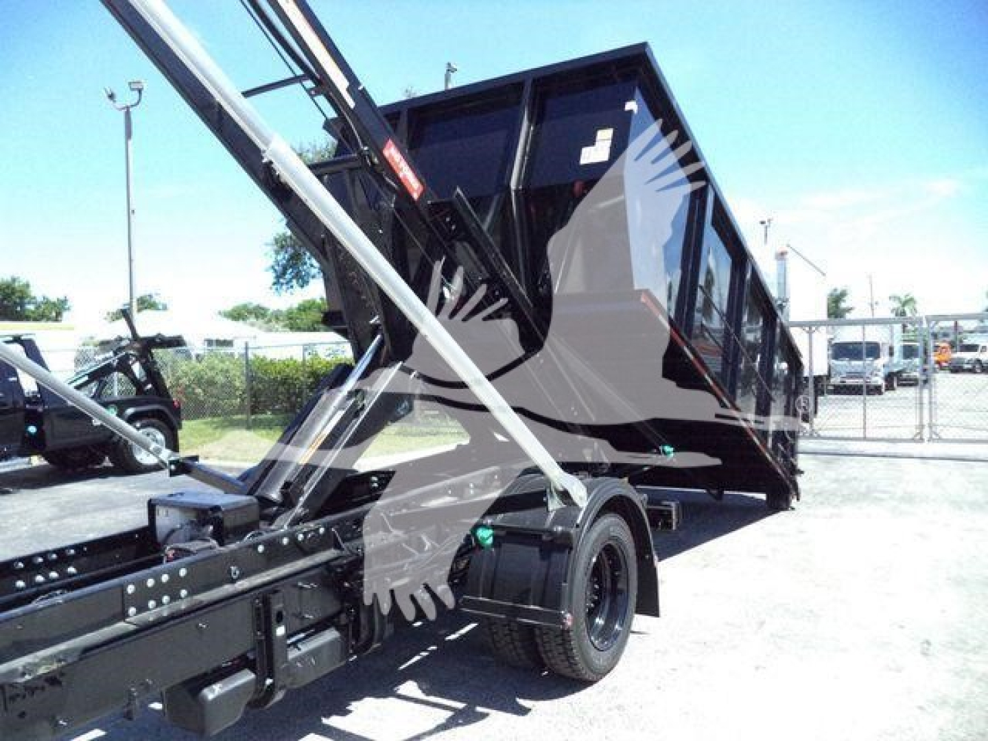 Truck bed and hydraulic system of a 2023 Chevrolet Silverado 6500HD roll-off truck showing hydraulic arms and cargo container.