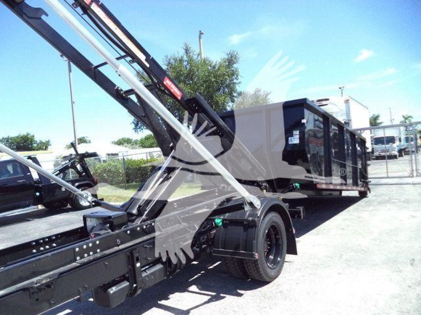 2023 Chevrolet Silverado 6500HD rolloff truck with hydraulic crane arm and trailer bed, visible wheels and side panels.
