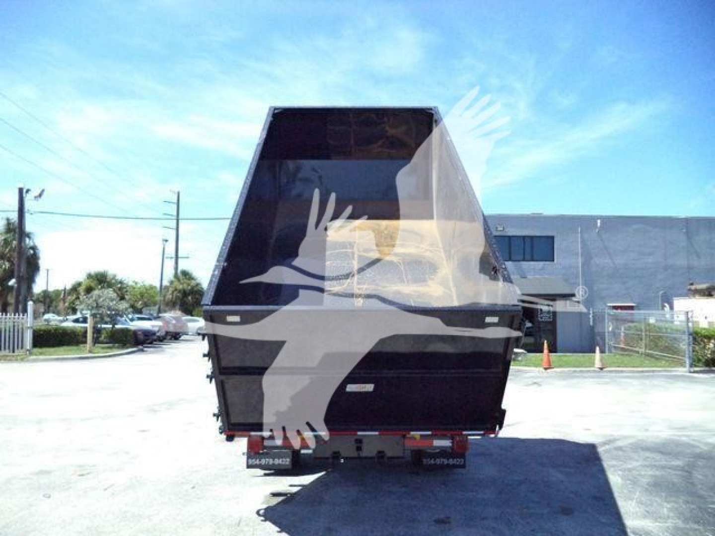 Truck dump bed with rear view showing dump trailer in a dealership lot.