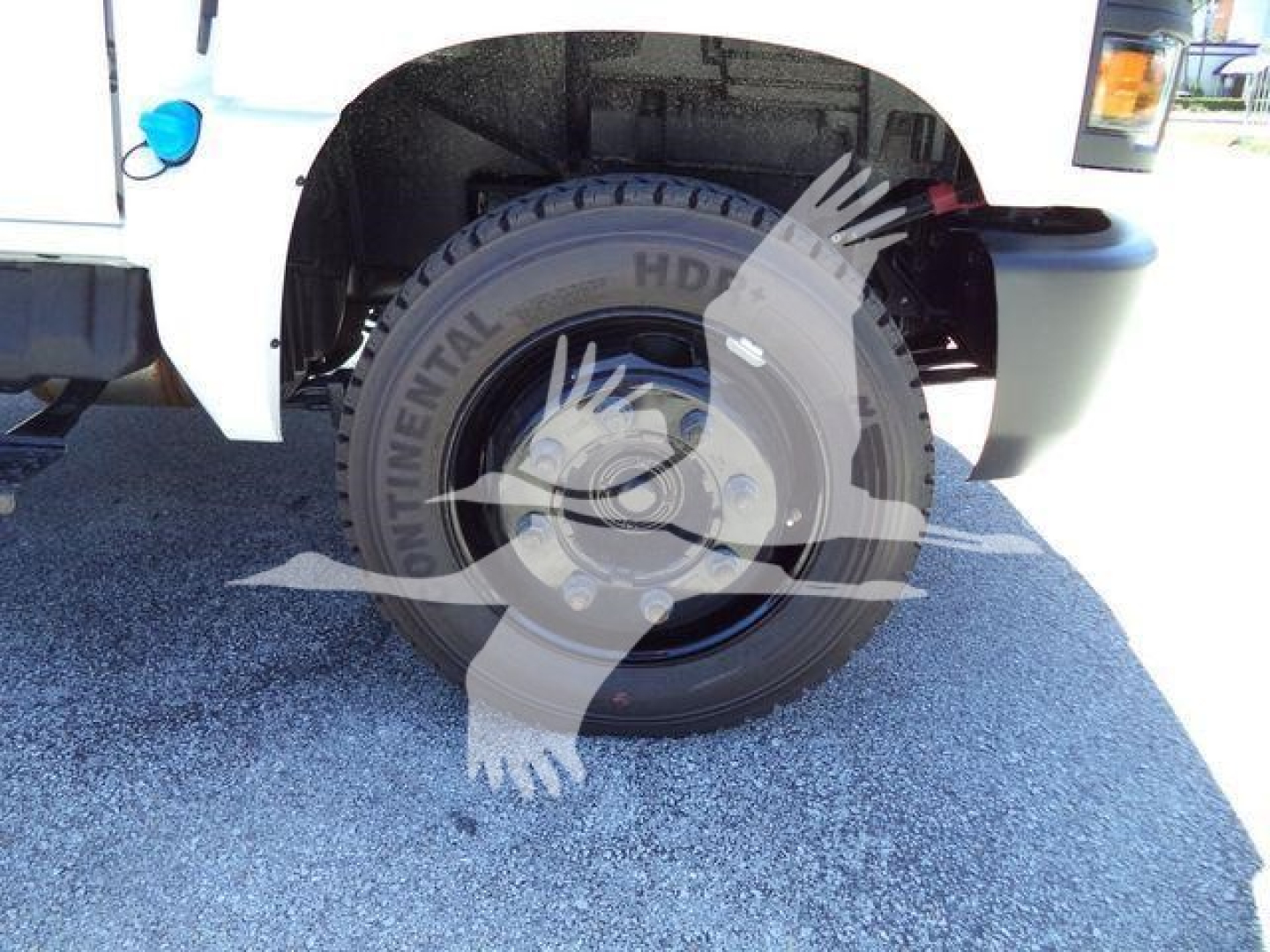 Truck wheel and front fender of a 2023 Chevrolet Silverado 6500HD with large off-road tire and black steel wheel, partial front bumper visible.